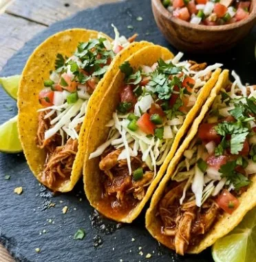 Slow cooker chicken tacos topped with fresh cilantro and lime