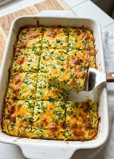Delicious cheesy shredded zucchini casserole served in a baking dish