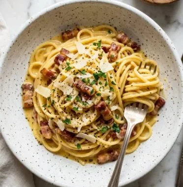 Bowl of homemade spaghetti carbonara topped with parmesan and parsley