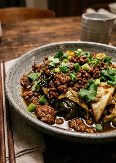 Plate of Mongolian ground beef cabbage stir-fry with green onions and sesame seeds.