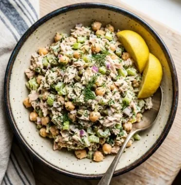 A bowl of 10 Minute Chickpea Tuna Salad, garnished with fresh herbs.