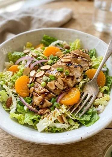 A vibrant bowl of Asian sesame chicken salad with fresh vegetables and sesame dressing.