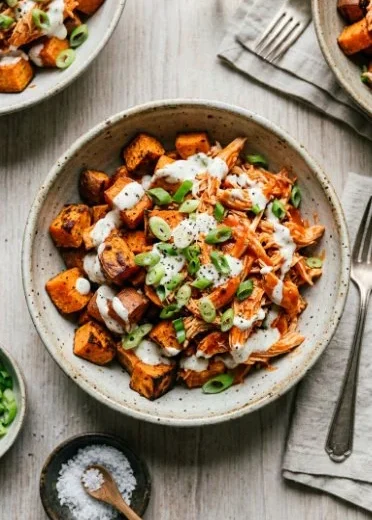Delicious Buffalo Chicken Sweet Potato Casserole topped with cheese and fresh herbs