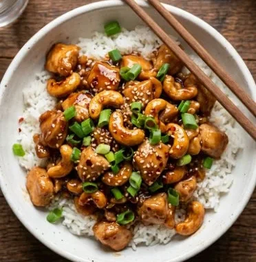 Cashew Chicken 1 Plate of cashew chicken garnished with vegetables and served over rice