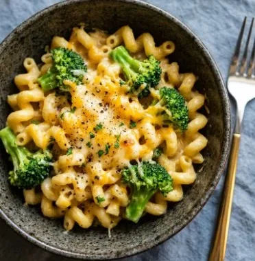 Cheesy and Creamy Broccoli Pasta 1 Cheesy and creamy broccoli pasta served in a bowl, garnished with basil.
