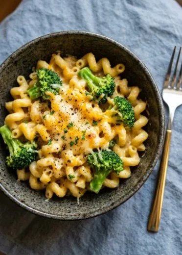 Cheesy and creamy broccoli pasta served in a bowl, garnished with basil.