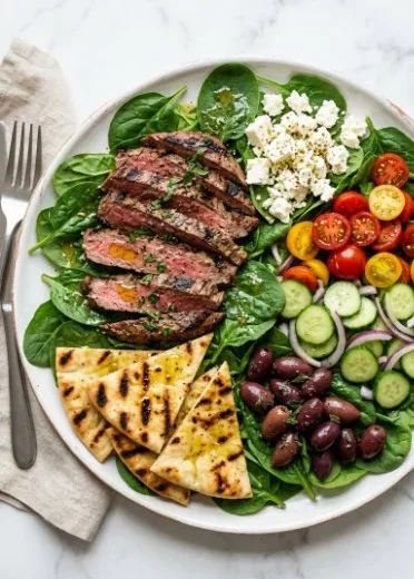 A colorful grilled steak salad topped with fresh vegetables and a tangy dressing.