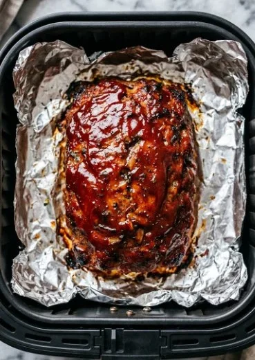 Delicious air fryer meatloaf served with mashed potatoes and green beans.