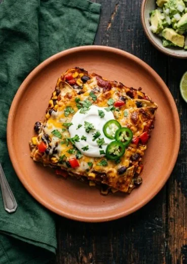 Black bean enchilada casserole topped with pumpkin chipotle sauce served in a dish.