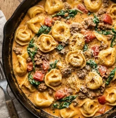 Creamy Spinach Beef Tortellini 1 Creamy spinach beef tortellini dish garnished with fresh herbs