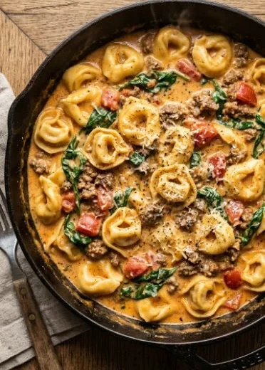 Creamy spinach beef tortellini dish garnished with fresh herbs