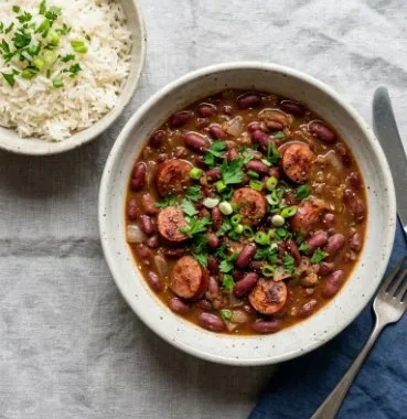Bowl of easy red beans and rice with spices and herbs, garnished and ready to serve.
