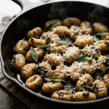 Black Garlic Gnocchi: The Cozy Umami Pasta You'll Make on Repeat 9 Black garlic gnocchi in a cast-iron skillet topped with Parmesan and fresh sage